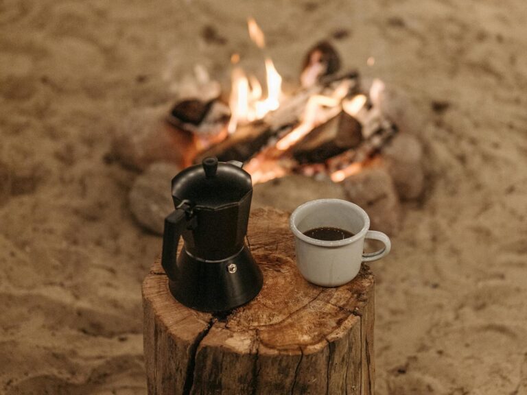 A Cup of Coffee on a Wooden Log Near the Bonfire